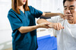 © Nuttapong punna - Female physiotherapist supports arm movement exercise for senior male patient during rehabilitation. Elderly care