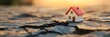© olga_demina - Miniature house model is standing on dry cracked earth at sunset, representing concepts such as drought, earthquake aftermath, climate change impact, and real estate market instability