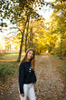 © Anhelina  - Young woman walking through an autumn park, looking back with a smile. Golden leaves cover the path, sunlight filtering through trees. Hair in motion adds energy and a joyful, carefree feel.