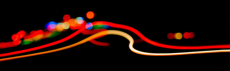 Wall Mural - Abstract glowing light streaks with vibrant bokeh effects against a dark void background, shallow depth of field at f/2.0, creating a dreamy and futuristic atmosphere.