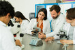 © AntonioDiaz - High school teacher helping students learn biology using microscopes in laboratory