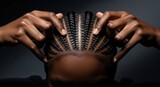 Close up view of intricate cornrow braids on a head with hands touching the hair