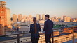 © stockbusters - Business people standing terrace looking at cityscape in golden sunset sunlight