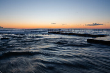 Wall Mural - flowing high tide water around wombarra rock pool, australia.
