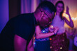 © qunica.com - A group of friends celebrate a birthday at home with music and dancing, enjoying a lively atmosphere under colorful lighting.