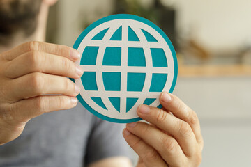 Leinwandbilder - Close-up of hands holding a teal paper cut-out of a world globe, representing internet connectivity.