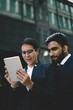 © BullRun - Focused diverse businesspeople watching tablet in street