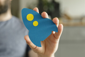 Aufkleber - Close-up of a hand holding a paper rocket, symbolizing new beginnings and innovation.