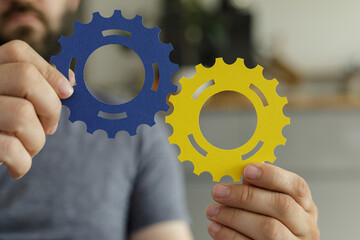 Aufkleber - Image of hands holding blue and yellow gears, symbolizing teamwork, collaboration, and synergy.