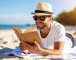 © David Andres - Un hombre joven con sombrero de paja y gafas de sol tumbado sobre una toalla en una playa y leyendo un libro. Vacaciones y relax