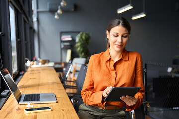 successful smiling latin hispanic young woman using pad computer for business app. busy executive ce