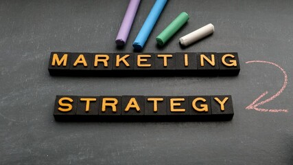 Wall Mural - marketing strategy concept. alphabet letters and chalk pieces on a blackboard background. 4k video