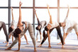 © Prostock-studio - Multiethnic group of young people performing yoga exersices in modern loft studio