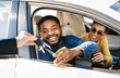 © Prostock-studio - This image depicts a happy couple receiving the keys to their new car from a dealership representative. The man is sitting in the drivers seat of a white sedan and is reaching out to take the keys