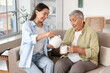 © Pixel-Shot - Happy young woman with her grandmother pouring tea at home