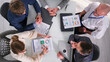 © chekart - The board of Directors is sitting at a table with papers and laptops, top view. They discuss ideas and work together on a project