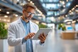 © tope007 - A man in a white lab coat is using a tablet computer