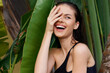 © SHOTPRIME STUDIO - Happy young woman in black swimsuit standing with hands on face smiling at camera