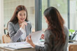 © aekachai - Two Asian businesswomen are sitting in a meeting, planning investment plans, business strategies. On the table are documents and graphs.
