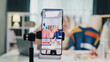 © tirachard - Close-up phone screen record Asia lady vlogger look phone camera review sweater new collection live selling online in IG story reel tiktok work at home studio. Business online media concept.