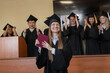 © Михаил Решетников - Happy Caucasian woman holds red diploma and classmates support her.