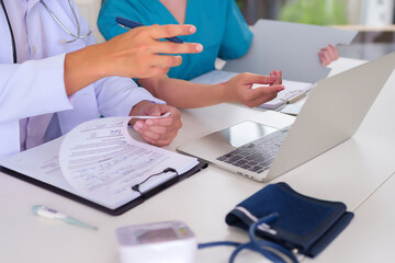 Wall Mural - Adult Doctors in Consultation Examining Patient Records on Laptop Discussing Diagnosis Treatment and Healthcare Solutions for Improved Health Outcomes