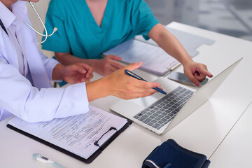 Wall Mural - Doctors Collaboration on Patient Information Using Laptop for Healthcare Solutions and Treatment Planning for Asian Adult Women's Health