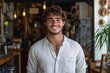 © Focus Jazz - Young man standing proudly at the entrance of his coffee shop, welcoming customers and guests to experience his new business venture with a warm smile and confident posture, Generative AI