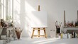 © Toko - Sunlit artist's studio with blank canvas on easel, surrounded by paint, brushes, and art supplies on white tables against a white wall