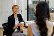 © David - Two happy asian women holding coffee cup work in the office, talking or casual meeting during coffee break