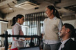 © qunica.com - A group of business people interacting in a modern office setting. Two women and a man smile as they engage in conversation, showcasing a positive work environment.