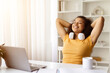 © Anastasiya - Smiling African American woman relaxing at her home desk after study, happy young black female leaning back in her chair with eyes closed and headphones around her neck, enjoying break