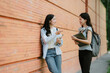 © PSG - Two Asian female students happily walk and talk at a university after class