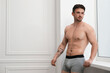 © New Africa - Young man in stylish light grey underwear near white wall indoors. Space for text