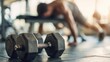 © The Little Hut - Dumbbells on Gym Floor With Man Doing Push-Ups in Background, Representing Strength Training and Fitness Motivation : Generative AI