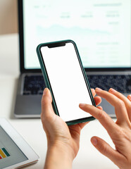 Close-up female hands using smartphone on background of laptop on desk