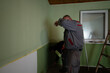 © qunica.com - Two workers engaging in an indoor painting project, applying green paint to walls, and creating a newly refreshed and improved look with their dedicated effort.