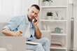 © SHOTPRIME STUDIO - A focused man engaged in a phone call while taking notes at home, showcasing a contemporary and productive lifestyle. Perfect for business and work-from-home themes.