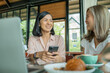 © sutlafk - two cheerful and beautiful girls are sitting together near the table and watching something on the phone. they look relaxed and happy. also girls are enjoying the time spending together.