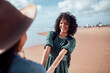 © Marko Geber - Young woman smiling and holding hands with a friend on a sunny beach