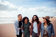 © Marko Geber - Group of four diverse friends laughing and walking on a sunny beach