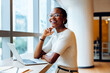 © (JLco) Julia Amaral - Smiling professional seated at a desk with a laptop in an office
