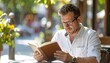© LesaMurina Coll - Man reads a book on a bright day at an outdoor cafe, enjoying leisure time