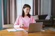 © muse studio - Young Woman Engages in Online Learning While Smiling at Her Laptop in a Cozy and Stylish Living Room During the Afternoon