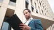 © VAKSMANV - Successful busy businessman wearing suit reading plan and checking time. Handsome beautiful attentive male staying outside of office holding reading documents. Successful concept.