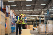 © Wanwajee - White and black co-worker have conversation about work flow at aisel wth warehouse background behide.