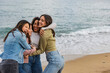 © PintoArt - Four young women embracing on beach, celebrating friendship and happiness