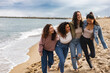 © PintoArt - Four young women walking and laughing on the beach