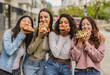 © PintoArt - Cheerful young women eating pizza slices in the city