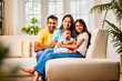 © StockImageFactory - Loving infant in her lap, sister shares joyful moment with family sitting indoors on modern sofa